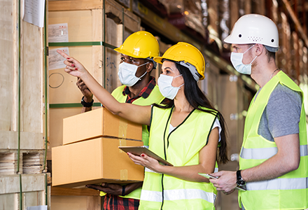 Three workers in factory wearing face masks and hard hats.