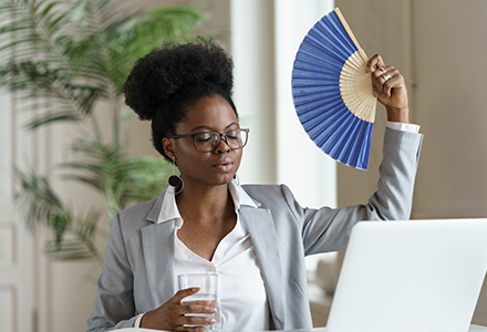 Office worker using hand fan in summer heat