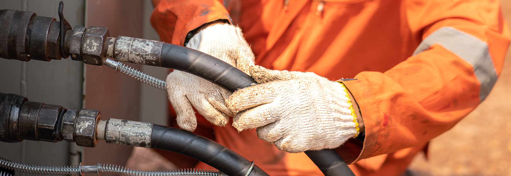 worker tending to hydraulic hoses