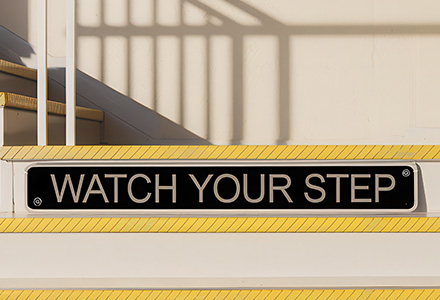 Stairs with a "Watch your step" sign on display