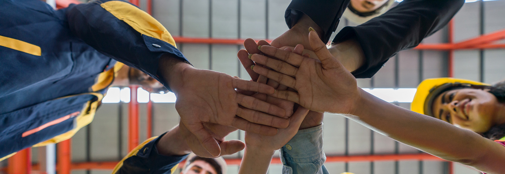 Diverse male and female factory workers joining hands