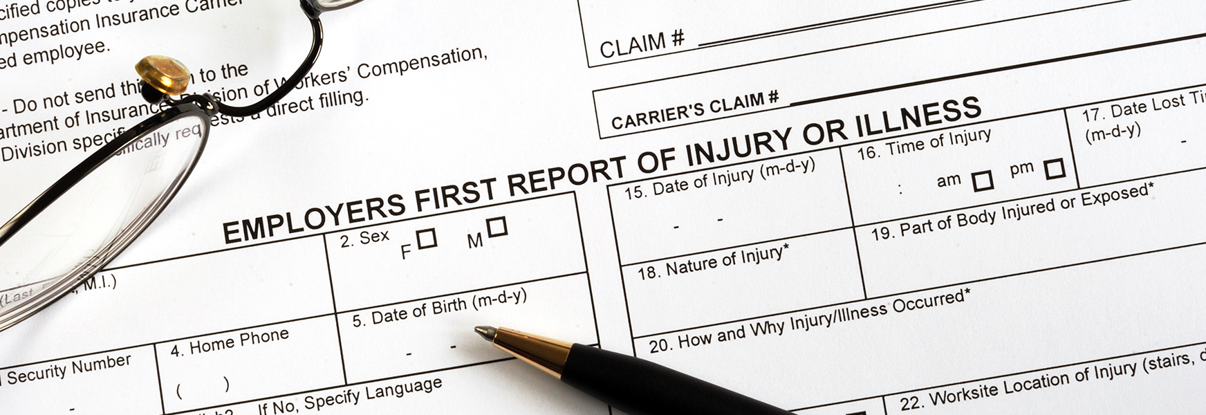 First report of injury form and pen sitting on a desk