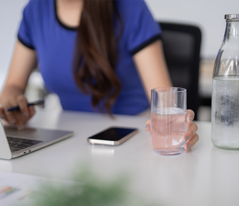 Woman in office reaching for a glass of water