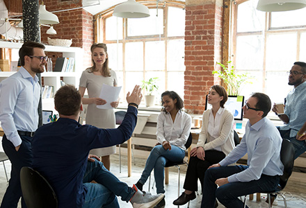 Man raising hand to ask question to diverse workers in office