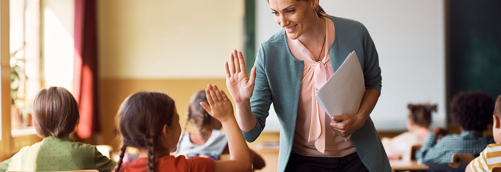 Classroom teacher and young student sharing a high-five