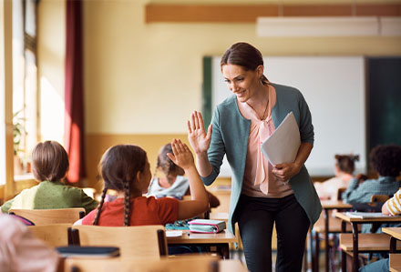 Classroom teacher and young student sharing a high-five