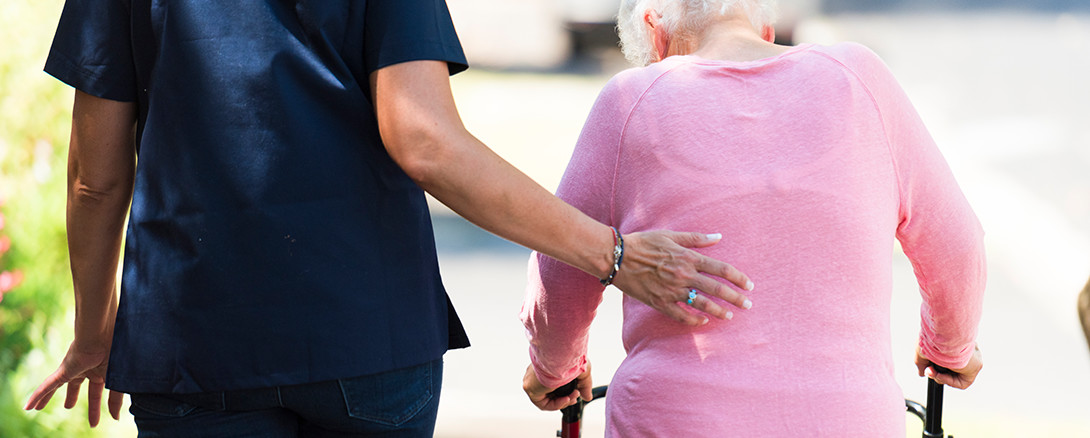 healthcare giver helping senior with walker